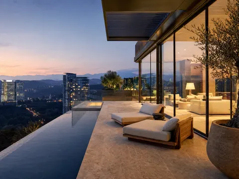 Penthouse Cielo: terraza con alberca angosta, camastros, olivos y barandal de vidrio sobre las torres y barrancas arboladas de Santa Fe, con las montañas del Valle de México al atardecer