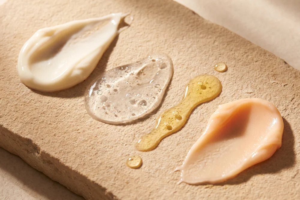 Texturas de crema, gel, aceite y bálsamo sobre una piedra arenisca